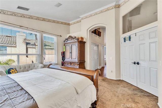 bedroom featuring light carpet, ornamental molding, and a closet