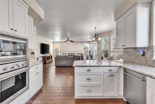 kitchen with white cabinetry, decorative light fixtures, stainless steel appliances, light stone countertops, and decorative backsplash