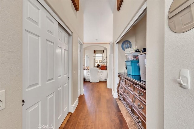 corridor with beamed ceiling and dark wood-type flooring