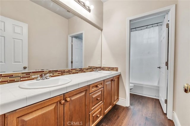 full bathroom with toilet, wood-type flooring, vanity, shower / bathtub combination with curtain, and backsplash