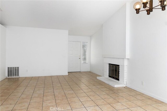 unfurnished living room with a fireplace, light tile patterned floors, and an inviting chandelier