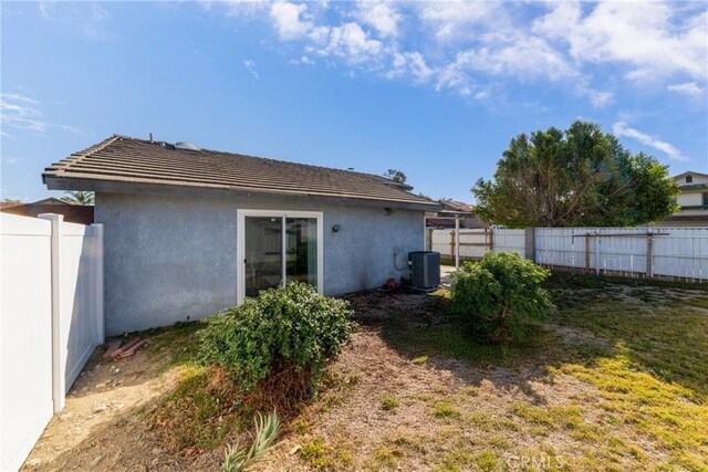 rear view of property featuring a yard and central air condition unit