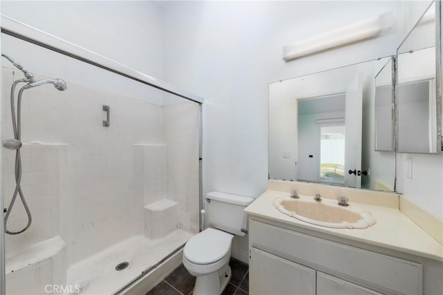 bathroom featuring tile patterned flooring, a tile shower, vanity, and toilet