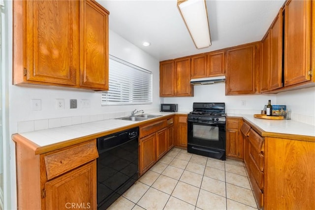 kitchen featuring tile countertops, sink, light tile patterned floors, and black appliances