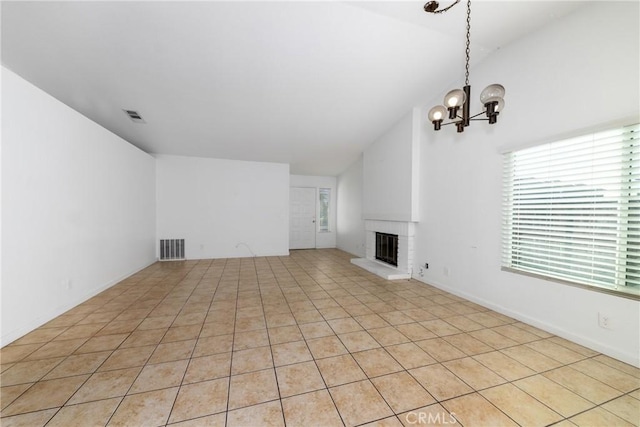 unfurnished living room featuring a brick fireplace, vaulted ceiling, an inviting chandelier, and light tile patterned floors