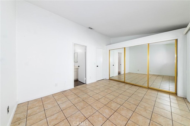 unfurnished bedroom featuring light tile patterned floors, connected bathroom, and a closet