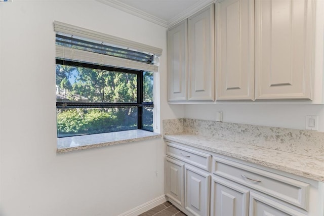 kitchen featuring tile patterned floors, white cabinetry, light stone counters, and ornamental molding