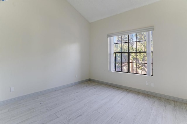 unfurnished room with light hardwood / wood-style floors and lofted ceiling