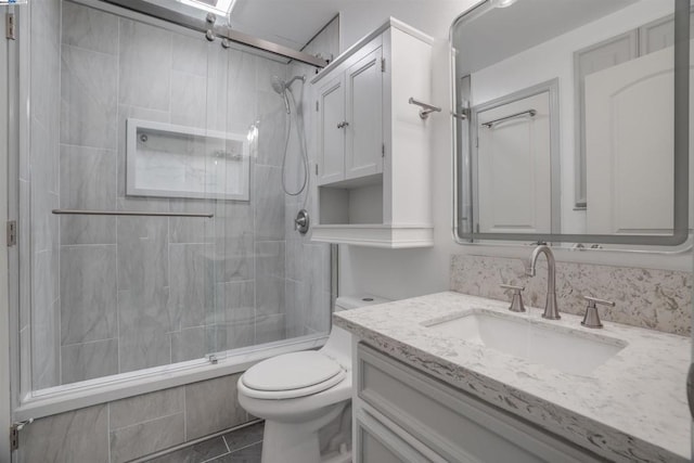 bathroom featuring tile patterned flooring, vanity, toilet, and a shower with shower door