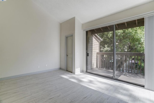 spare room featuring light hardwood / wood-style floors, a wealth of natural light, and vaulted ceiling