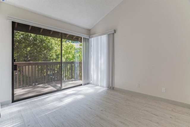 spare room with high vaulted ceiling, a textured ceiling, and light wood-type flooring