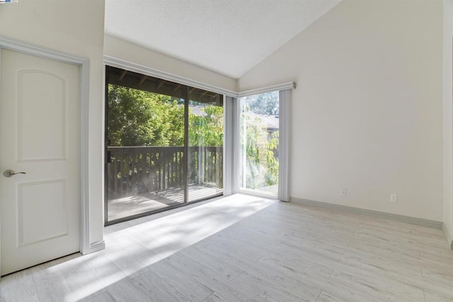 spare room with light wood-type flooring and high vaulted ceiling