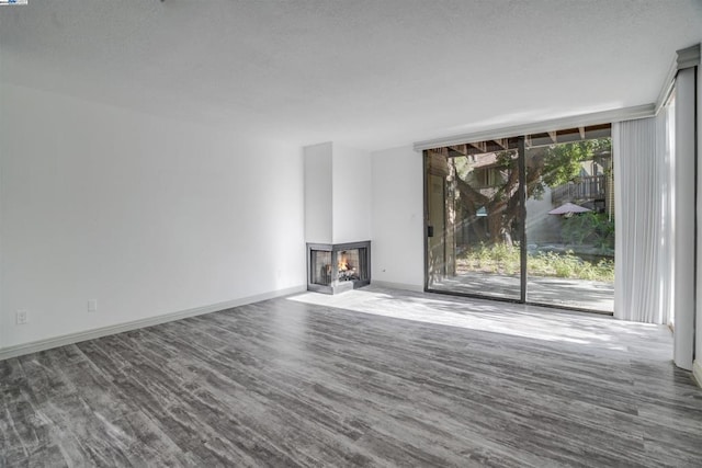 unfurnished living room featuring a multi sided fireplace and hardwood / wood-style floors