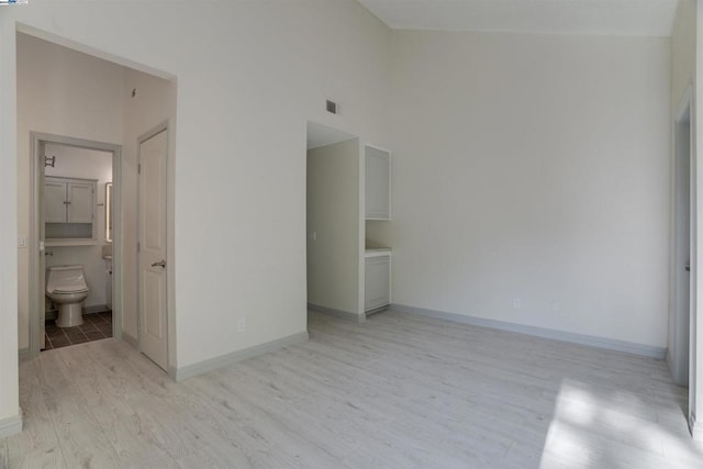 empty room with a high ceiling and light hardwood / wood-style flooring