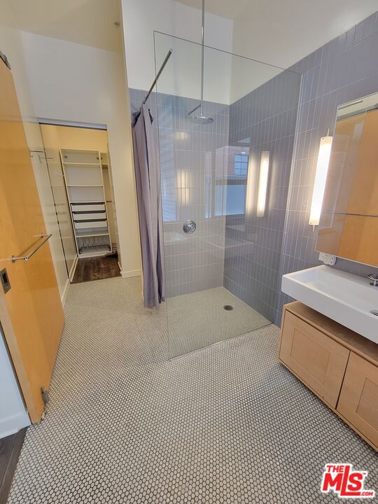 bathroom with tiled shower, vanity, and tile patterned flooring