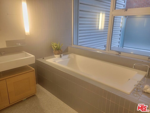 bathroom with sink, tiled bath, and tile patterned floors