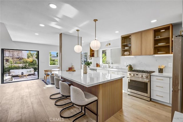 kitchen with white cabinets, pendant lighting, light wood-type flooring, and appliances with stainless steel finishes