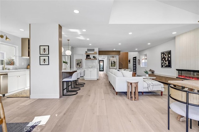 living room featuring a large fireplace, light hardwood / wood-style floors, and sink