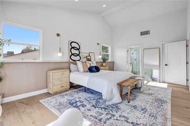 bedroom with beam ceiling, multiple windows, light hardwood / wood-style flooring, and high vaulted ceiling