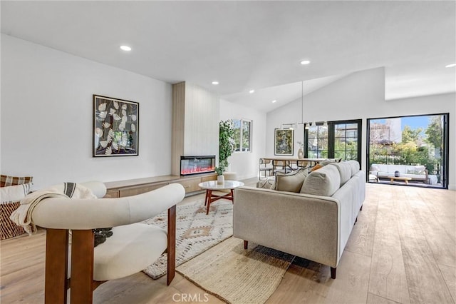 living room featuring a fireplace, light wood-type flooring, and high vaulted ceiling