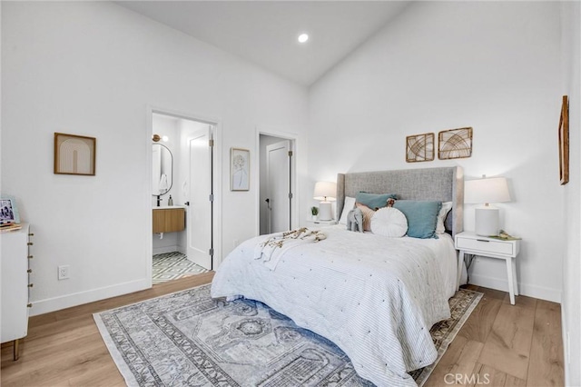 bedroom featuring connected bathroom, high vaulted ceiling, and light hardwood / wood-style floors