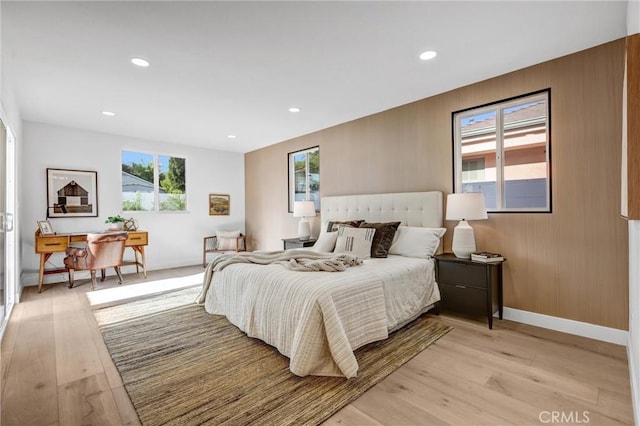 bedroom with wooden walls and light hardwood / wood-style flooring