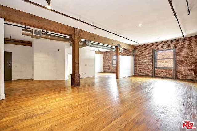 empty room featuring brick wall and light hardwood / wood-style flooring