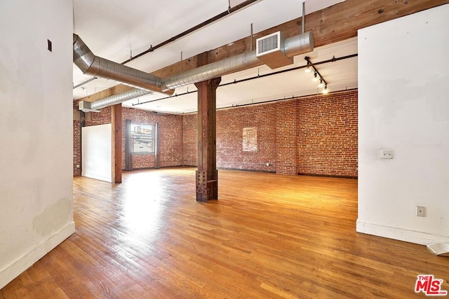 spare room with hardwood / wood-style floors and brick wall