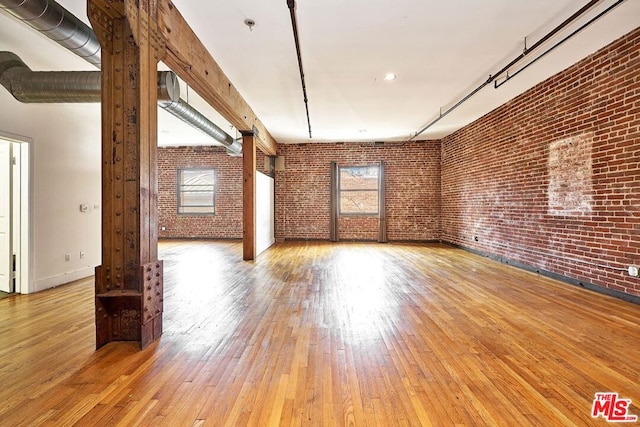 unfurnished room with wood-type flooring and brick wall