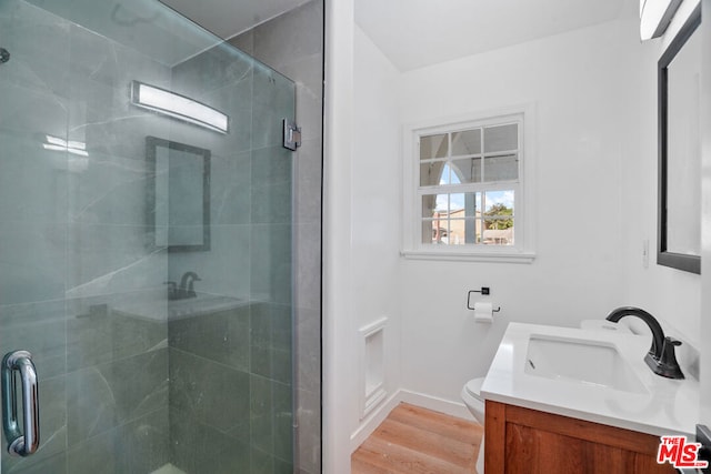 bathroom featuring hardwood / wood-style flooring, vanity, toilet, and a shower with door