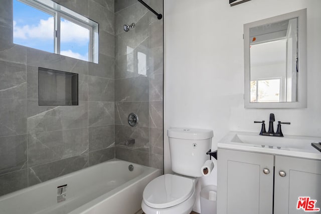 full bathroom with a wealth of natural light, toilet, vanity, and tiled shower / bath