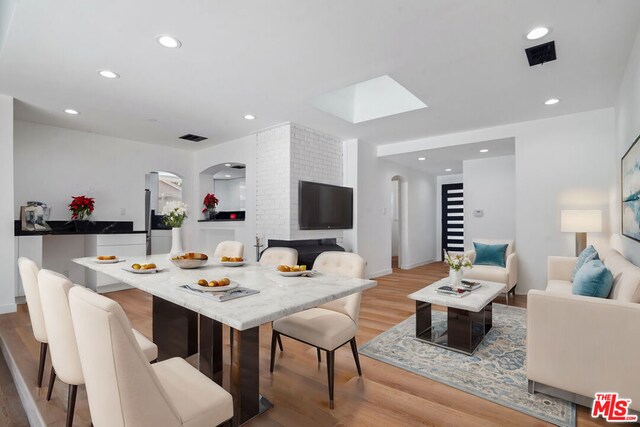 dining space with light wood-type flooring and a skylight