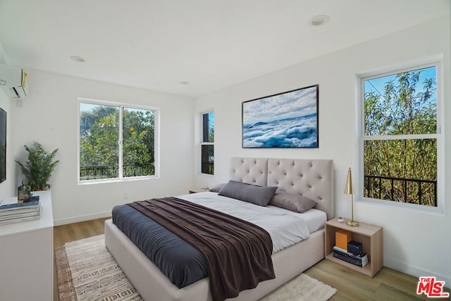 bedroom featuring light hardwood / wood-style flooring and a wall unit AC