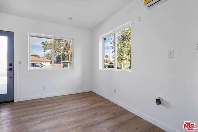 unfurnished dining area with an AC wall unit and hardwood / wood-style flooring