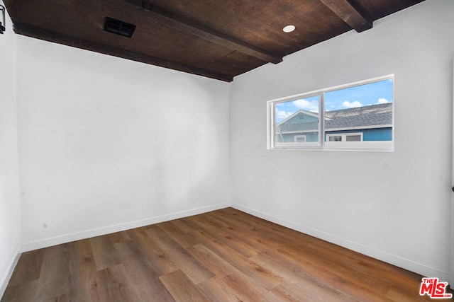 empty room with beamed ceiling, wood-type flooring, and wood ceiling