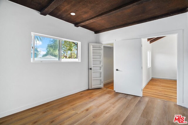 unfurnished bedroom with beamed ceiling, light hardwood / wood-style floors, and wooden ceiling