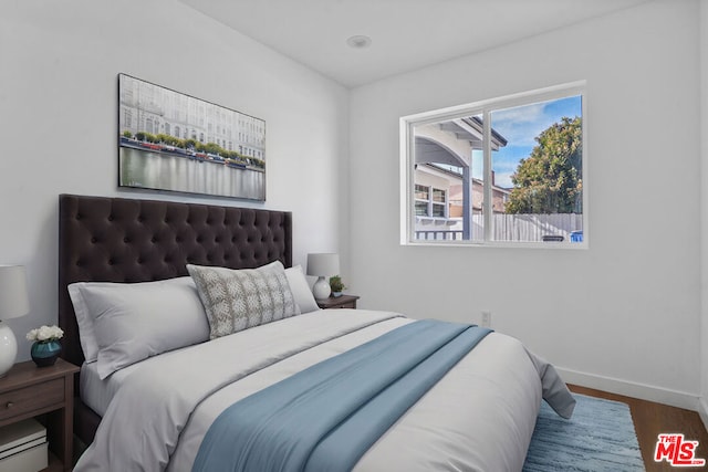 bedroom with dark hardwood / wood-style floors and baseboard heating