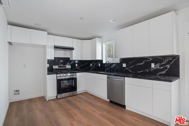 kitchen with sink, dark wood-type flooring, stainless steel appliances, backsplash, and white cabinets