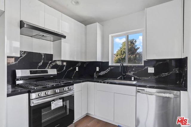 kitchen featuring sink, stainless steel appliances, backsplash, white cabinets, and exhaust hood