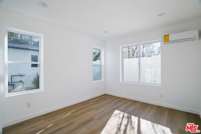 spare room with hardwood / wood-style floors and a wall unit AC