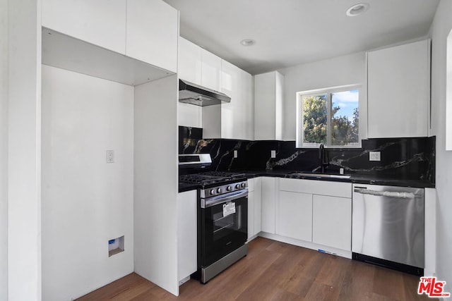 kitchen featuring appliances with stainless steel finishes, dark hardwood / wood-style flooring, extractor fan, sink, and white cabinets