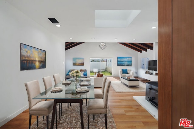 dining room with vaulted ceiling with beams and hardwood / wood-style flooring