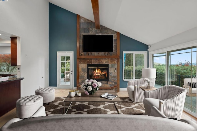 living room with high vaulted ceiling, plenty of natural light, beamed ceiling, and a tile fireplace