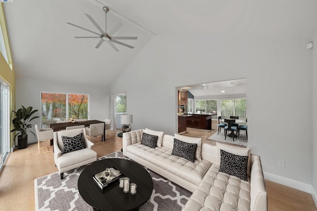 living room with ceiling fan, light hardwood / wood-style floors, and high vaulted ceiling