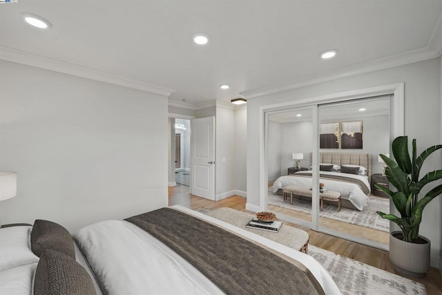 bedroom with a closet, crown molding, and light hardwood / wood-style flooring