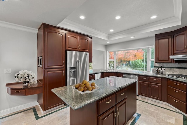 kitchen with appliances with stainless steel finishes, a kitchen island, sink, stone countertops, and a raised ceiling