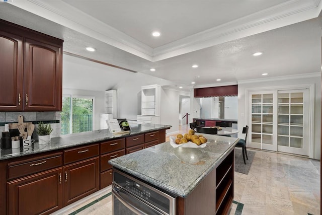 kitchen featuring a kitchen island, dark stone counters, tasteful backsplash, dark brown cabinets, and crown molding