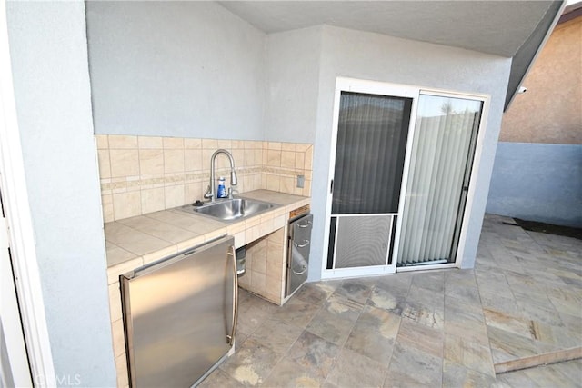 kitchen with tile countertops, dishwasher, and sink