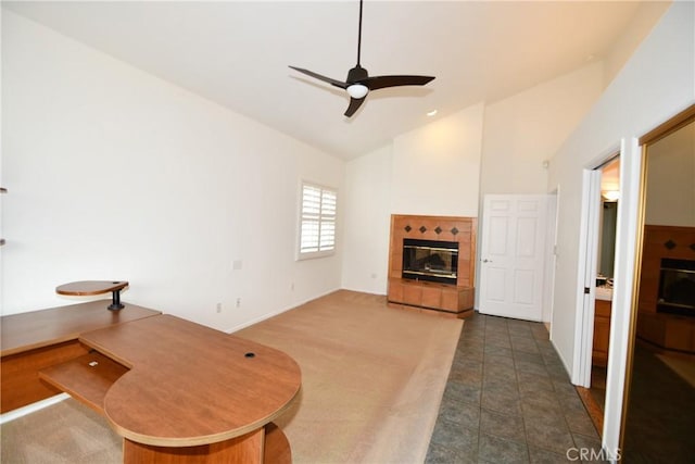 carpeted living room featuring a tile fireplace, ceiling fan, and high vaulted ceiling