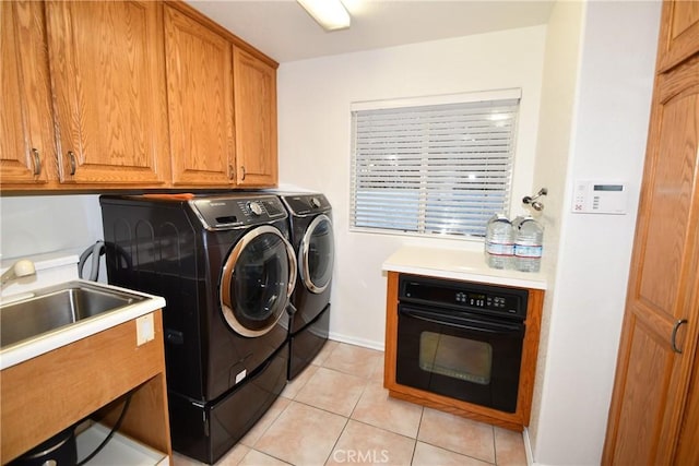 laundry room with washer and dryer, light tile patterned floors, cabinets, and sink